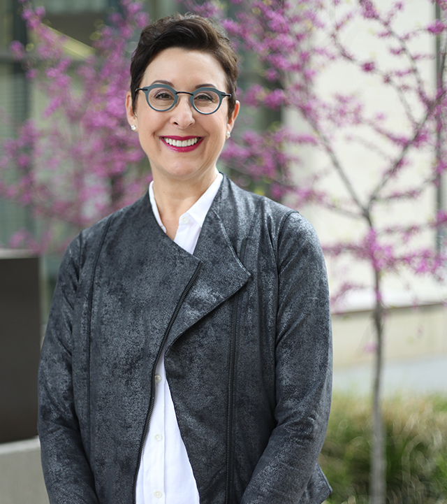 Amy, a Women's Health patient treated for vulvodynia, stands outdoors, smiling.