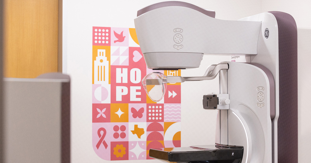 A mammogram machine in front of a colorful pink and burnt orange wall decal.