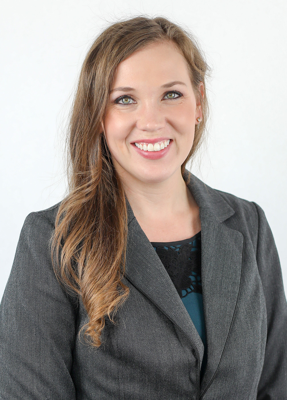 Alyssa Aguirre wearing a gray blazer and smiling in front of a white backdrop.