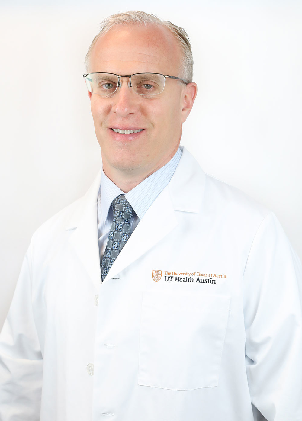 Orthopedic surgeon Kevin Bozic, MD, MBA, FAOA, FAAOS, wearing a white coat and smiling in front of a white backdrop.