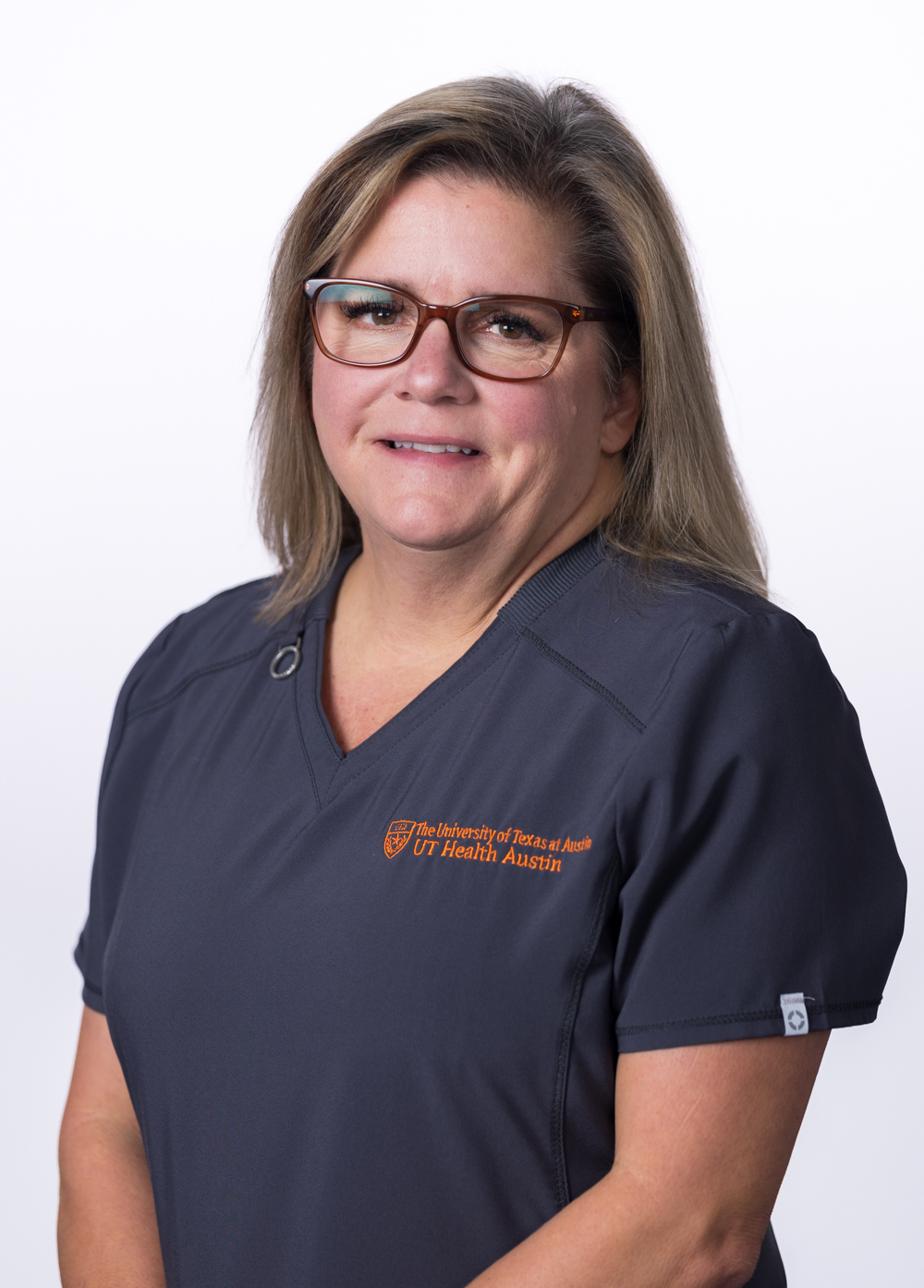 Sherry Bristow-Cruz wearing dark scrubs and smiling in front of a white backdrop.