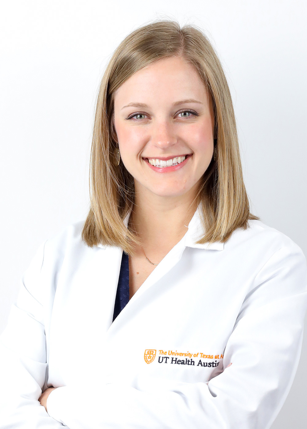 Emmy Feeler wearing a white coat and smiling in front of a white backdrop.