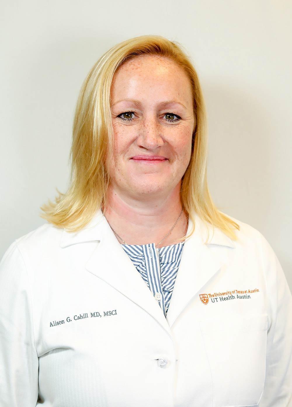 Maternal-fetal medicine specialist Alison Cahill, MD, MSCI, wearing a white coat and smiling in front of a white backdrop.