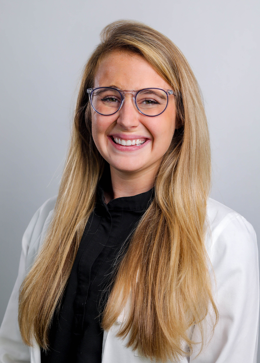 Amanda McKinney wearing a white coat and smiling in front of a white backdrop.