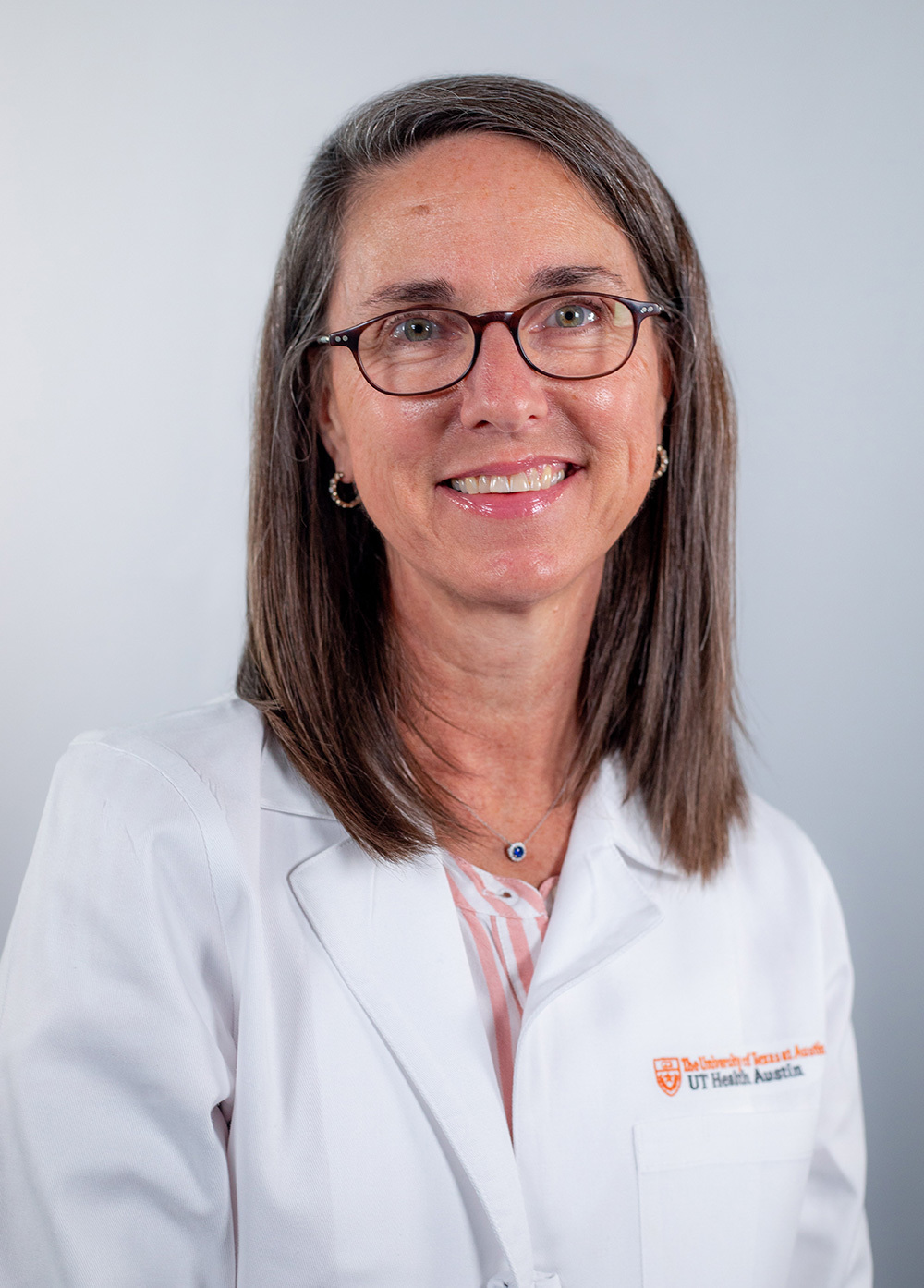 Nurse practitioner Amy Hemingway, DNP, CNS, CPNP AC/PC, wearing a white coat and smiling in front of a white backdrop.