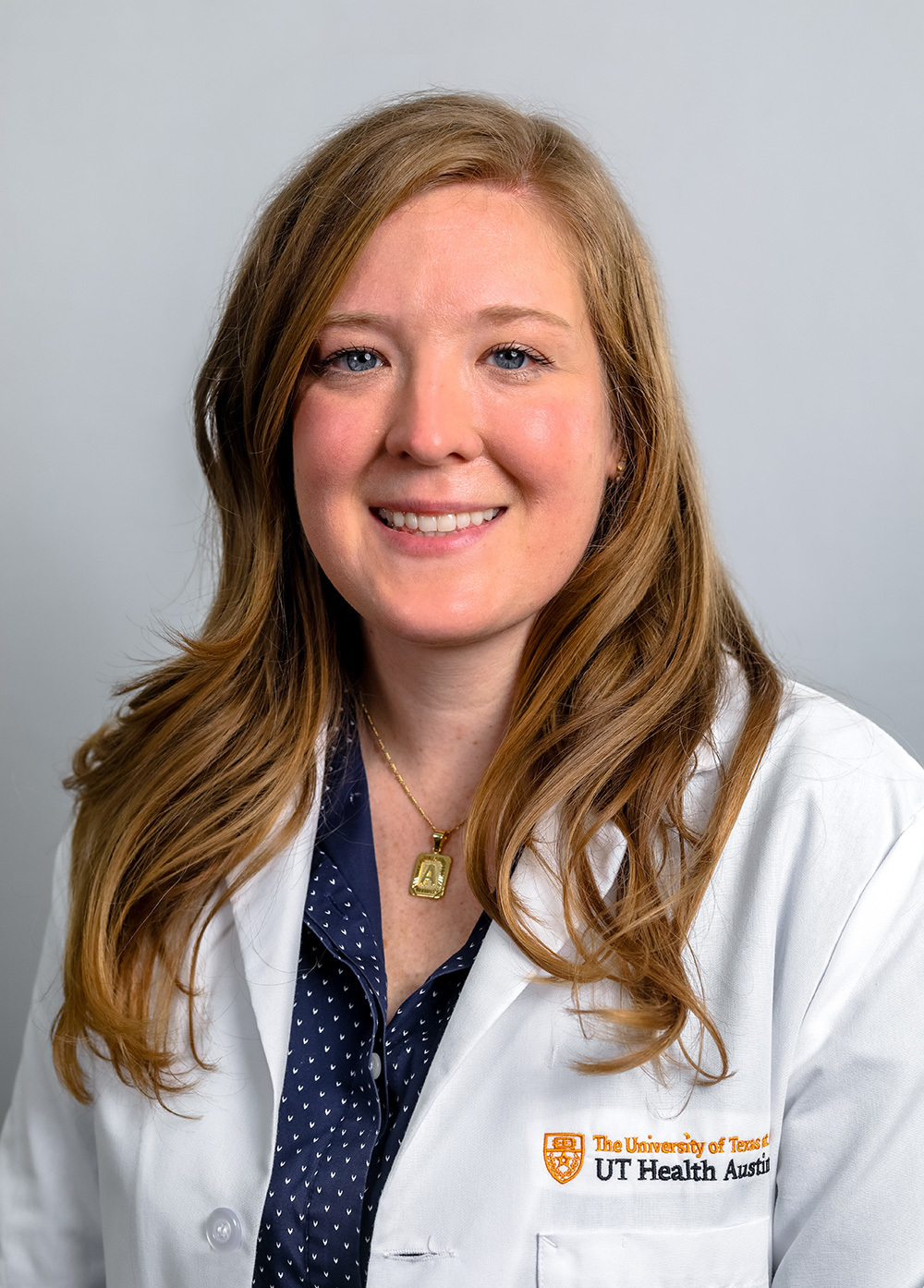 Acute care pediatric nurse practitioner Anna Brauninger, MSN, APRN, CPNP-AC, wearing a white coat and smiling in front of a white background.