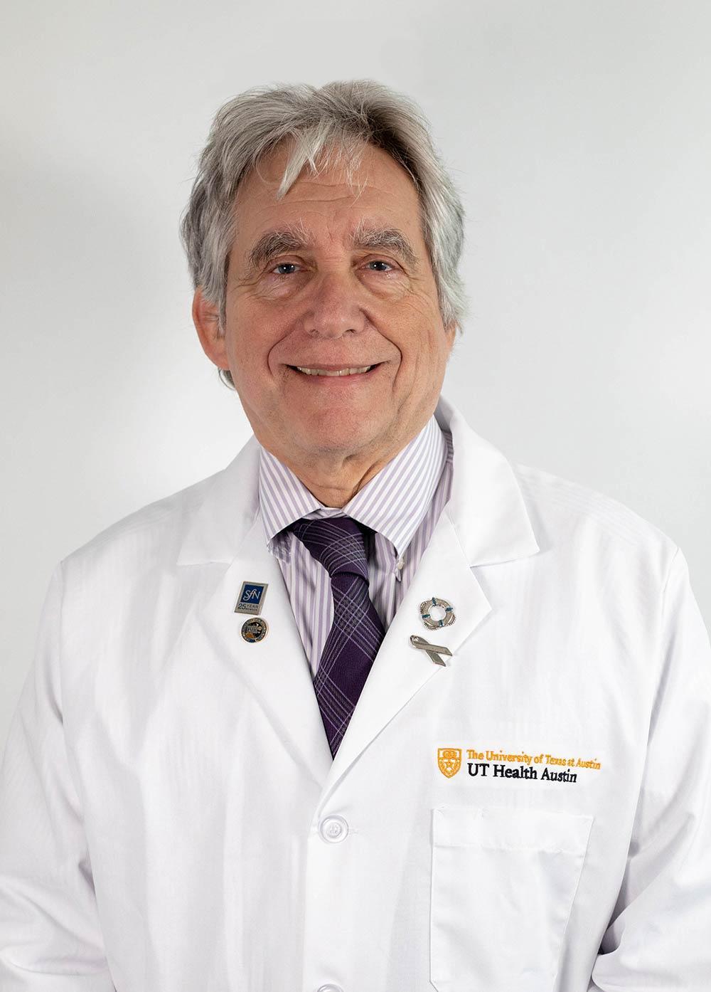 Dr. Charles Nemeroff wearing a white coat and smiling in front of a white backdrop.