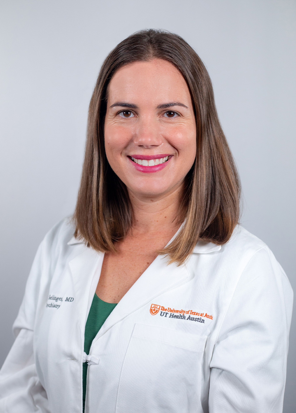 Pediatric psychiatrist Claire Selinger, MD, wearing a white coat and smiling in front of a white backdrop.