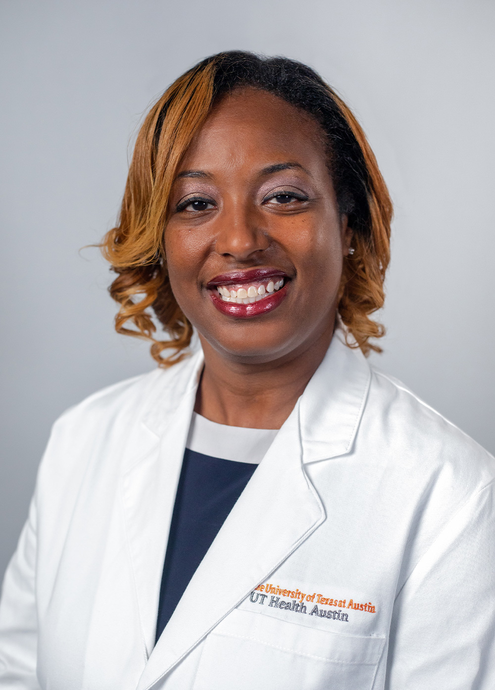 Dr. Cristal Brown wearing a white coat and smiling in front of a white background.