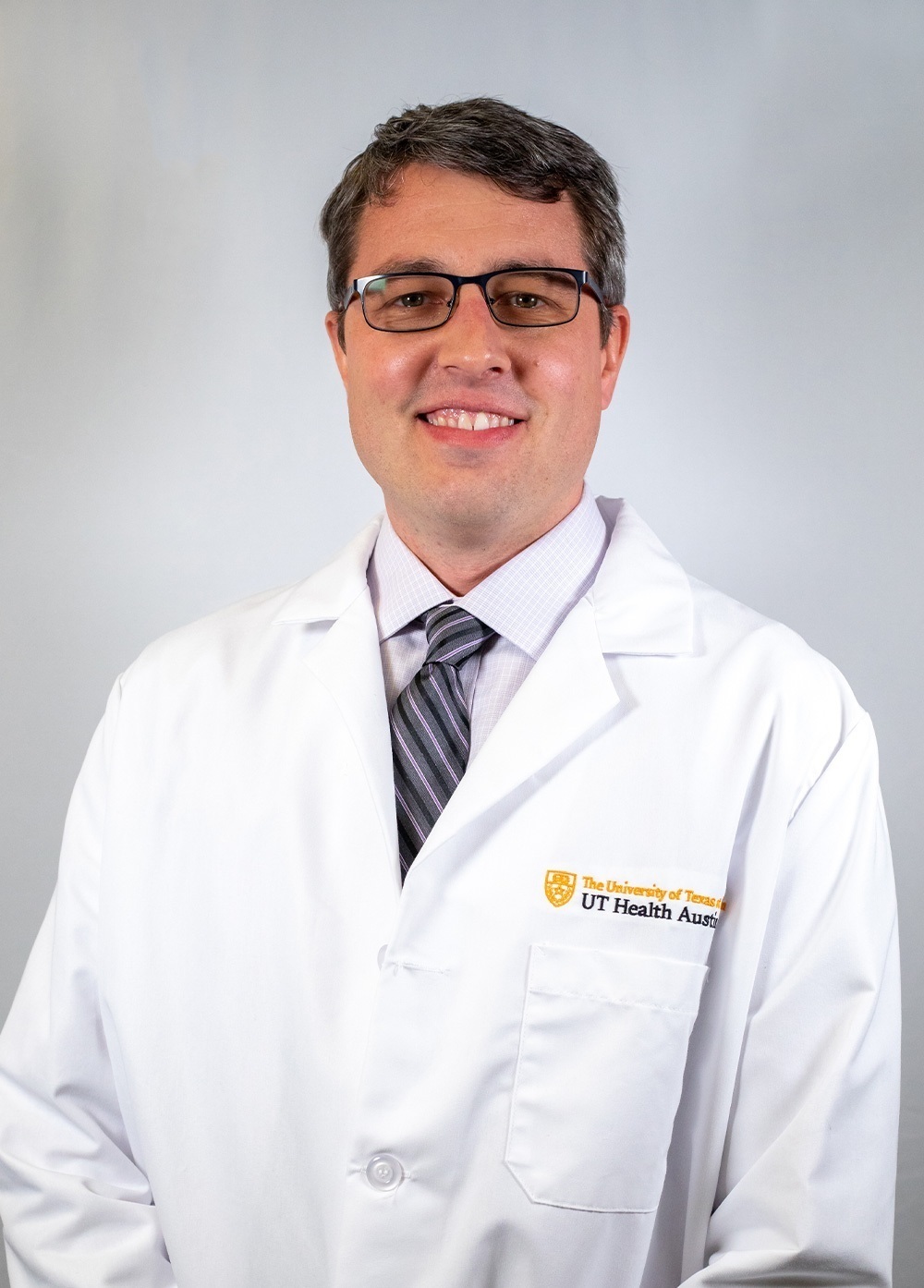 Psychologist David Heckler PhD, ABPP, wearing a white coat and smiling in front of a white backdrop.