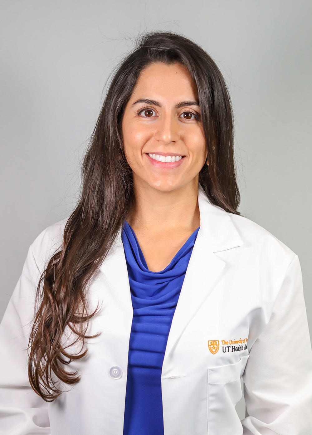 Diana Mendoza wearing a white coat and smiling in front of a white backdrop.