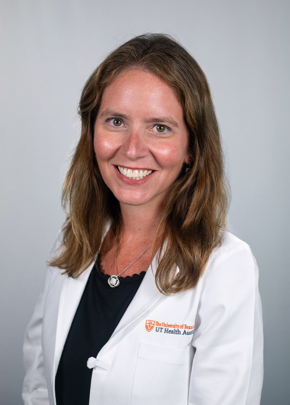 Pediatric neuropsychologist Emily Greenspahn, PhD, wearing a white coat and smiling in front of a white backdrop.