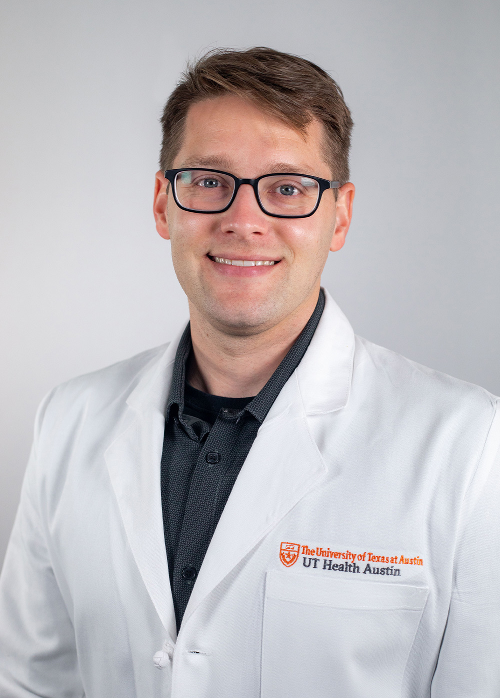 Ophthalmologist Eric Crowell, MD, MPH wearing a white coat and smiling in front of a white backdrop.