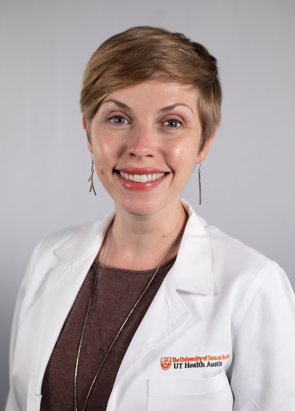 Erin Richardson wearing a white coat and smiling in front of a white backdrop.