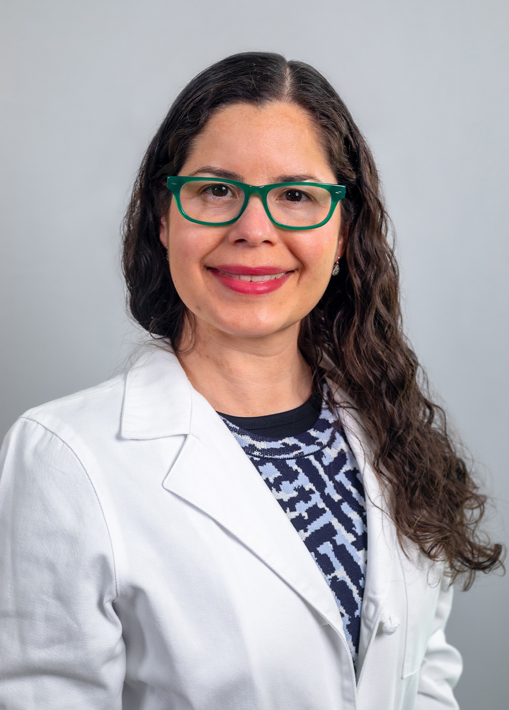 Dr. Glendaliz Bosques wearing a white coat and smiling in front of a white backdrop.