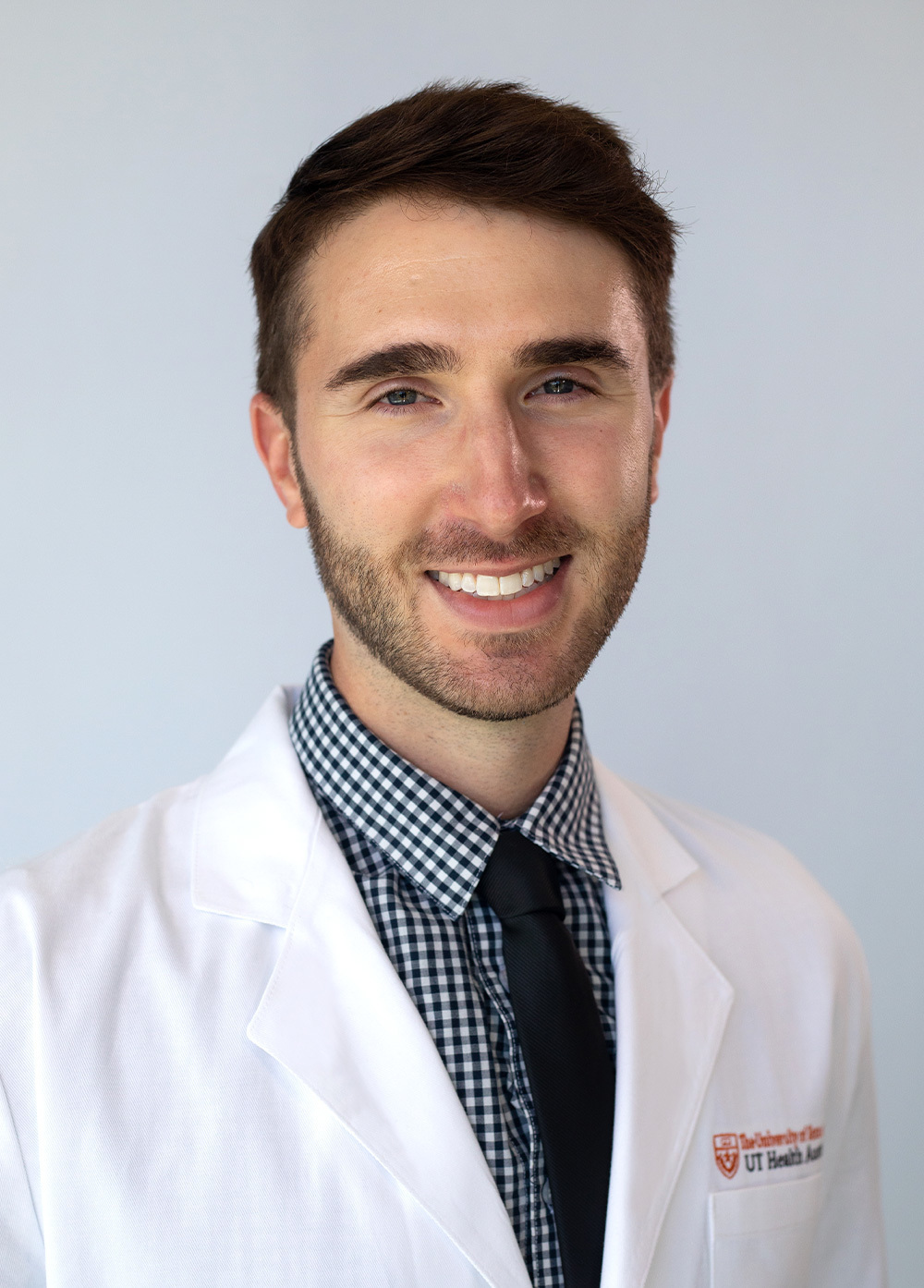 Physician assitant Jacob Rosenbaum, PA-C, wearing a white coat and smiling in front of a white backdrop.