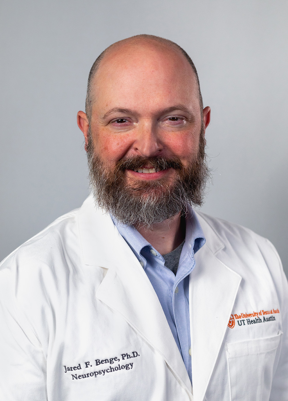 Dr. Jared Benge wearing a white coat and smiling in front of a white backdrop.