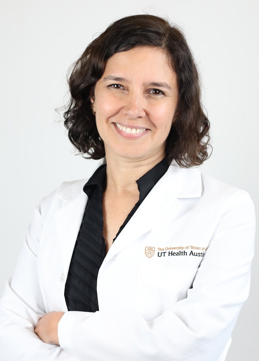 Dermatologist Jennifer Aranda, MD, wearing a white coat and smiling in front of a white backdrop.