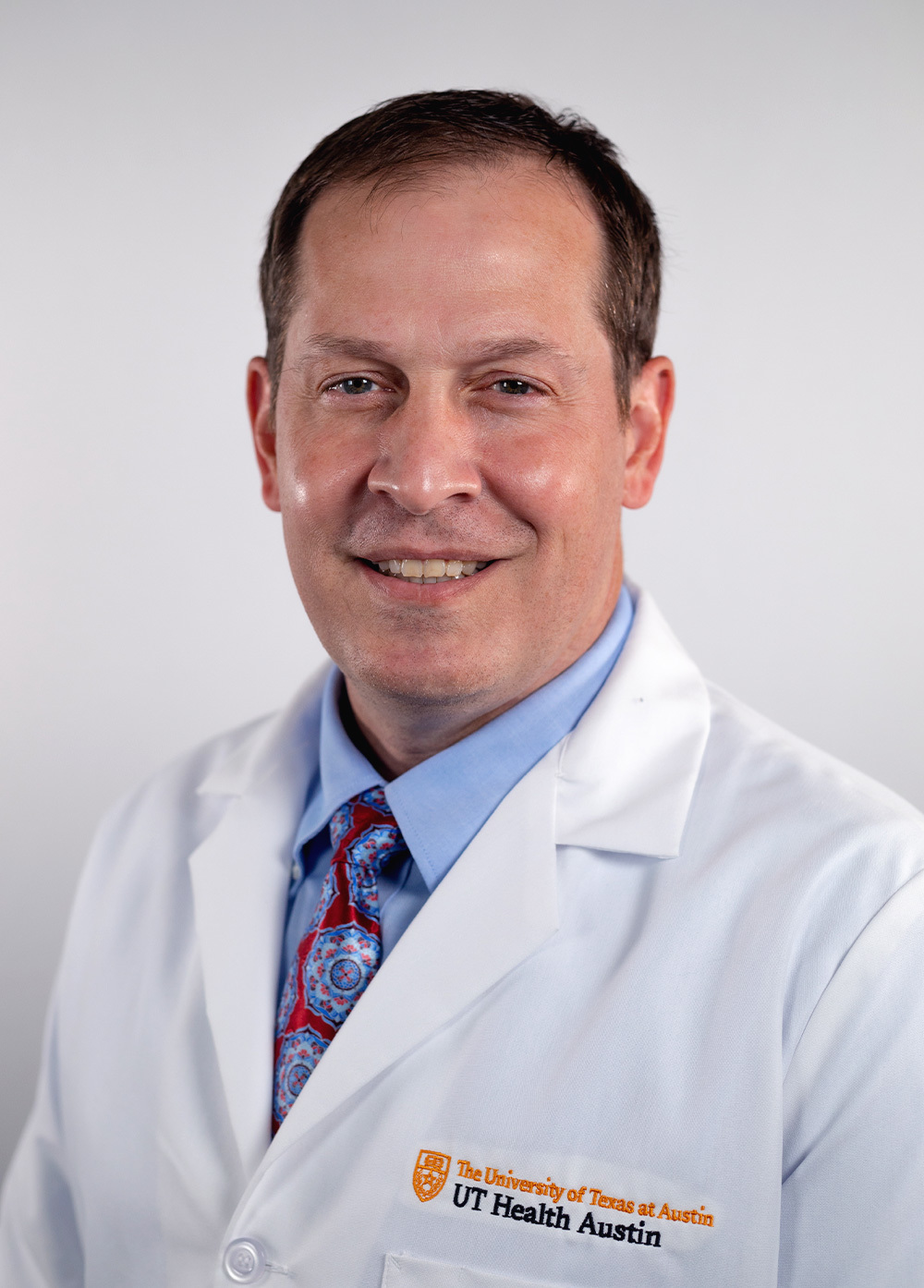 Dr. Jeremy Affolter wearing a white coat and smiling in front of a white backdrop.