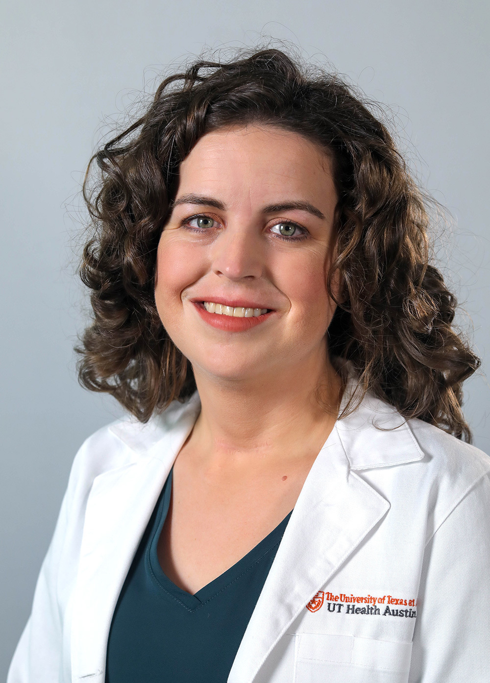 Dr. Jessica Pliego wearing a white coat and smiling in front of a white backdrop.