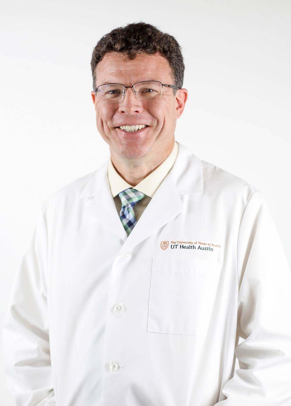 Dr. Johnathan MacClements wearing a white coat and smiling in front of a white backdrop.