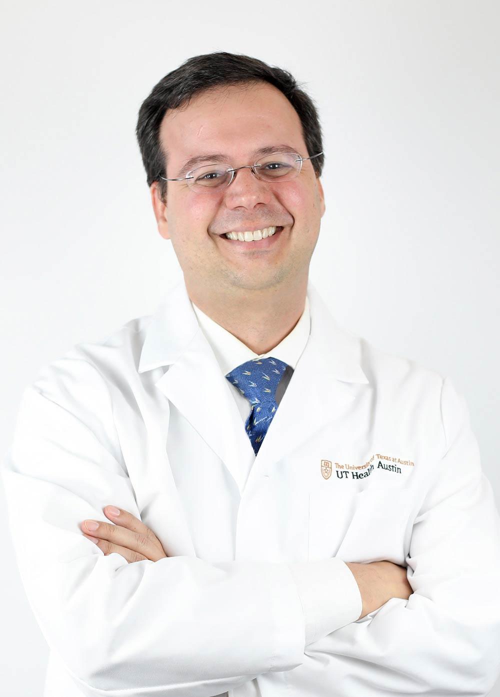 Dr. Jorge Almeida wearing a white coat and smiling in front of a white backdrop.