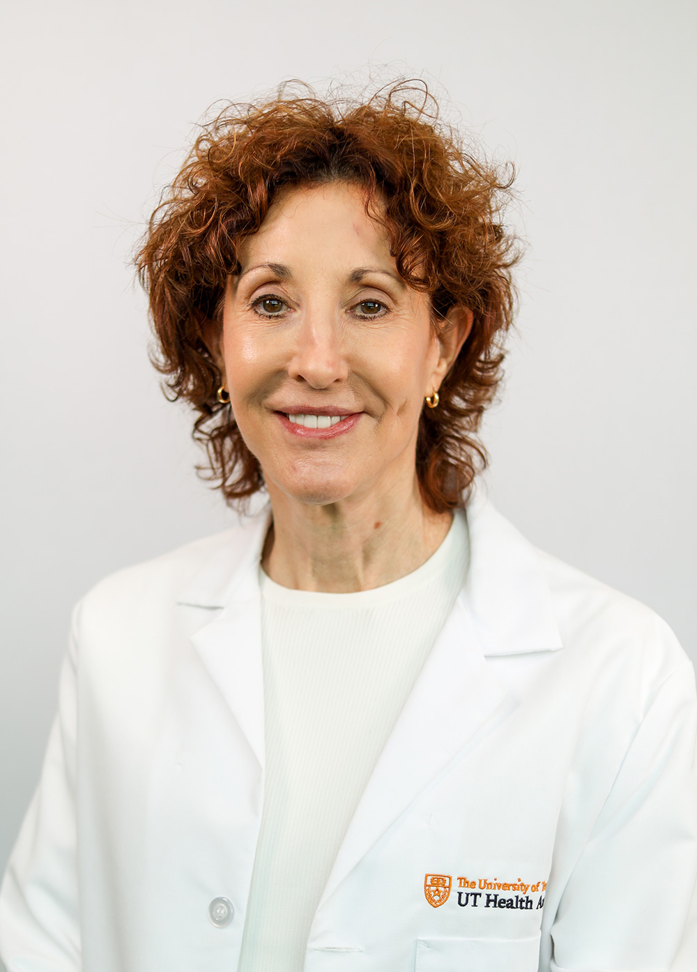 Dr. Julie Farrington wearing a white coat and smiling in front of a white backdrop.