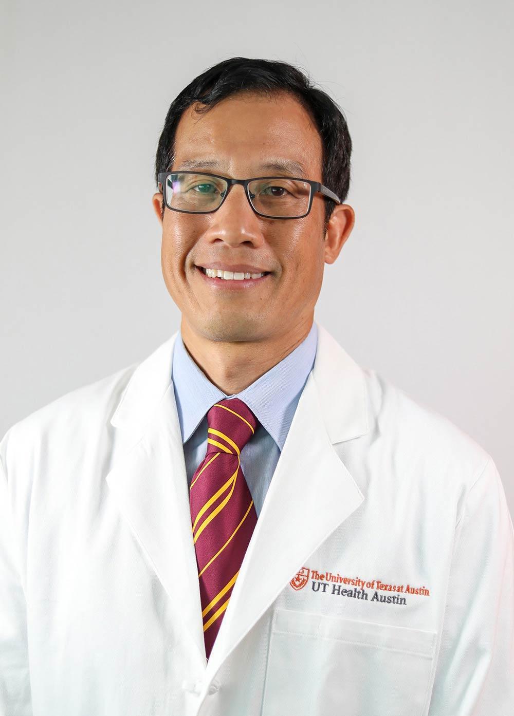 Dr. Karl Chiang wearing a white coat and smiling in front of a white backdrop.