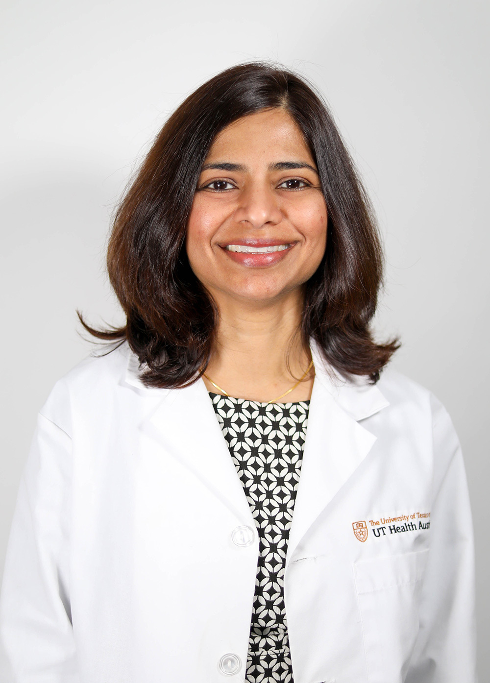 Gastroenterologist Kavitha Kumbum, MD, wearing a white coat and smiling in front of a white backdrop.