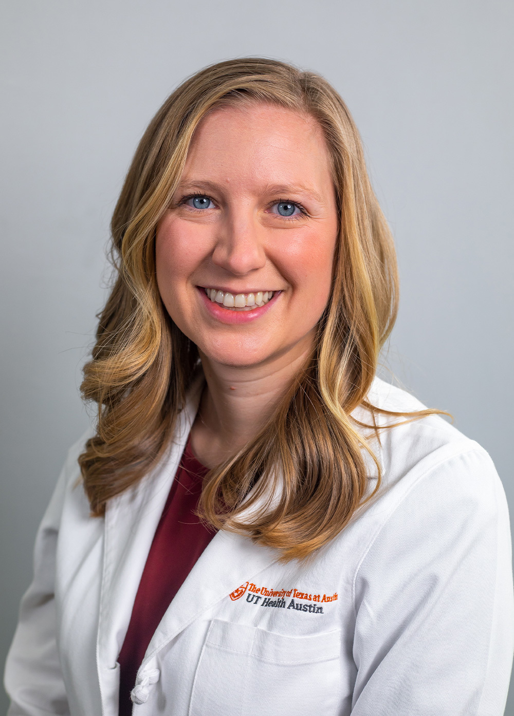 Pediatric psychologist Lindsey Elliott, PhD, wearing a white coat and smiling in front of a white backdrop.