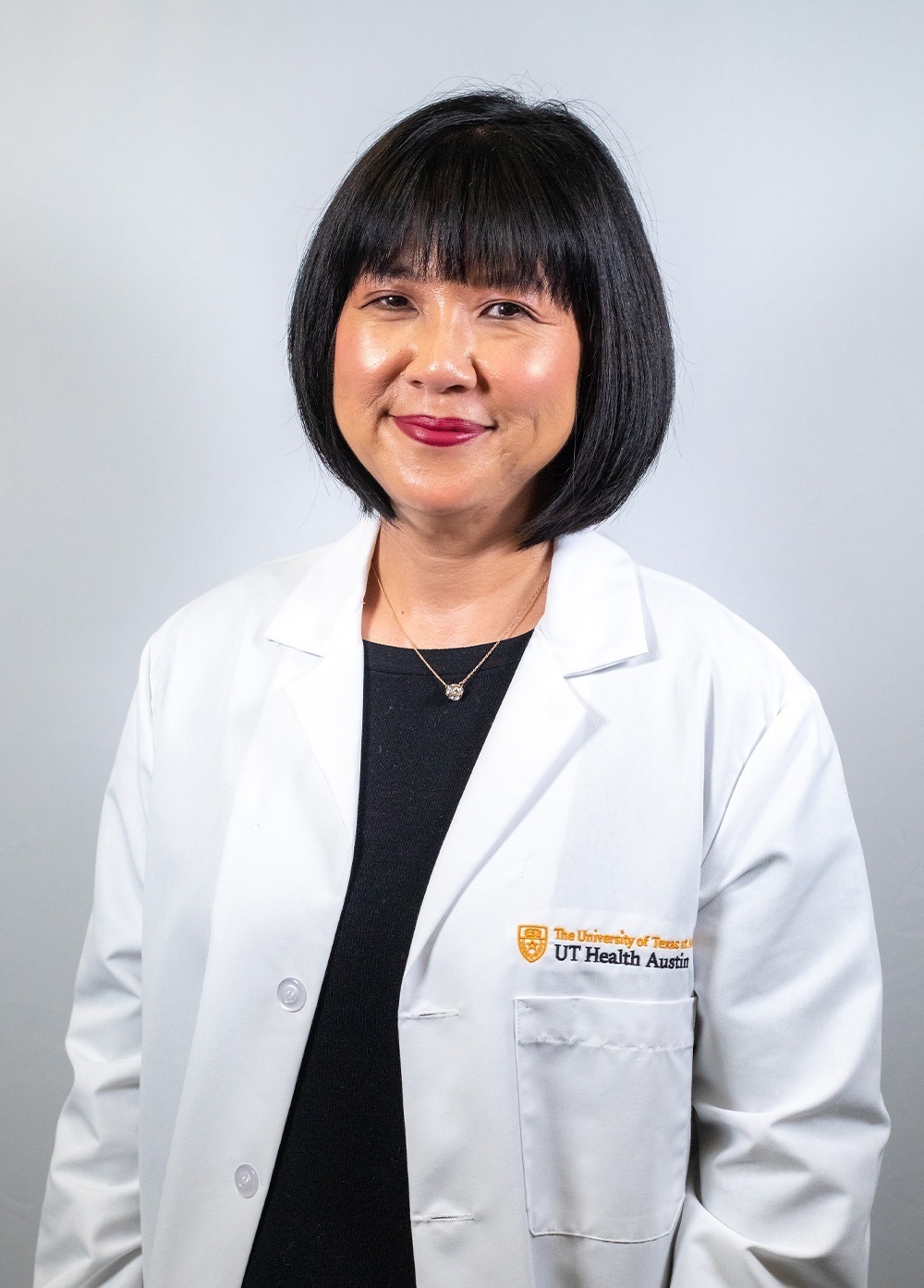 Pediatric psychologist Lynn Monnat, PhD, wearing a white coat and smiling in front of a white backdrop.