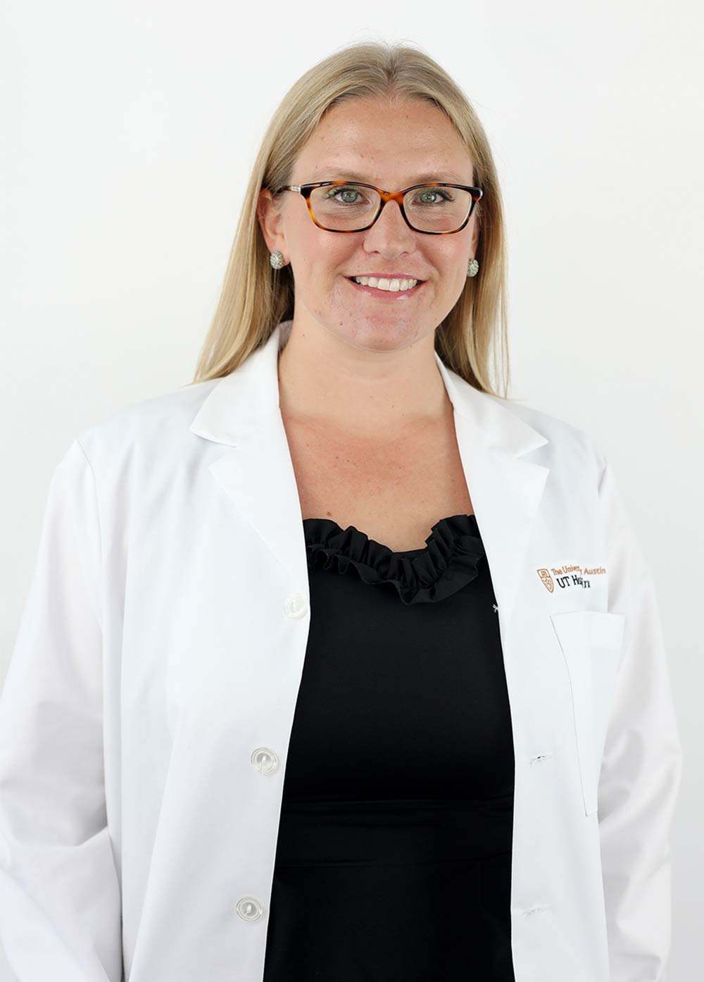 Obstetrician-gynecologist Margaret Whitney, MD, NCMP, wearing a white coat and smiling in front of a white backdrop.