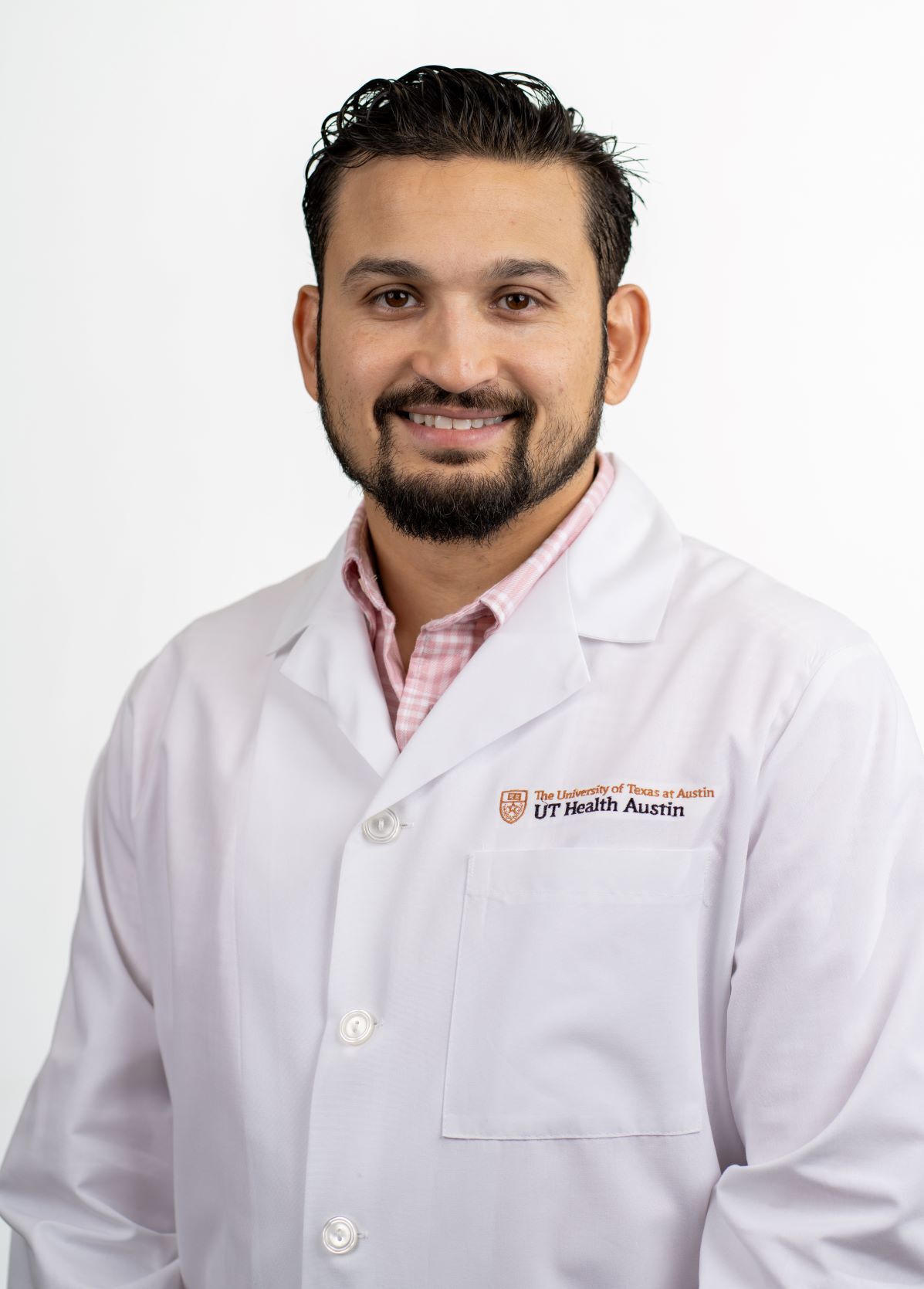 Dr. Omar Iqbal wearing a white coat and smiling in front of a white backdrop.