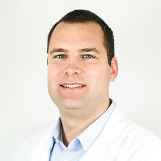 Dr. F. Parker Hudson wearing a white coat and smiling in front of a white backdrop.