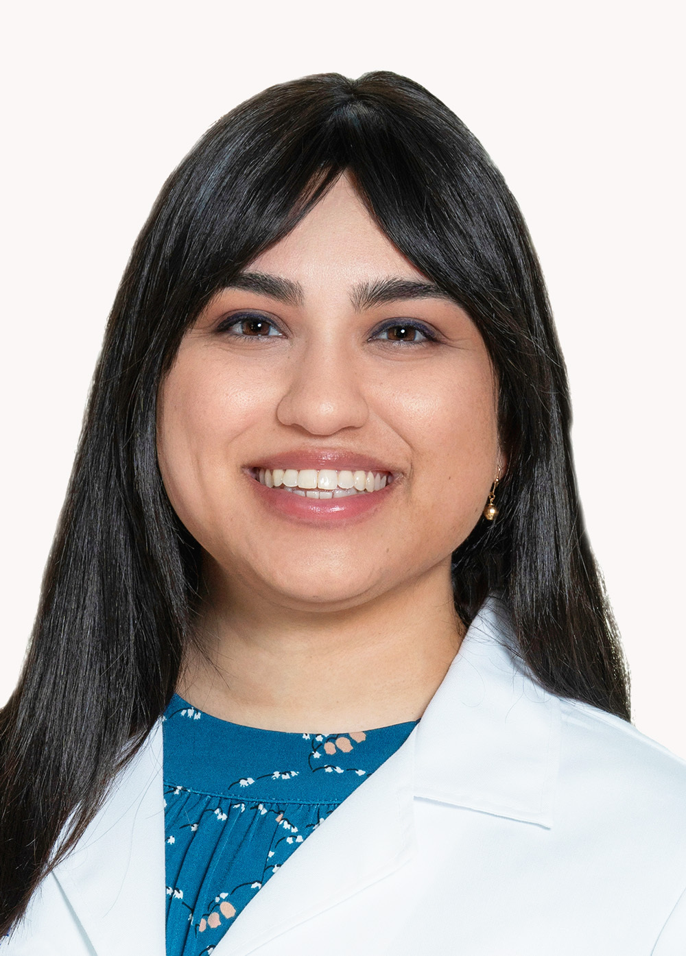 Board-certified psychiatrist Priya Kumar-Kaparaboyna, MD, wearing a white coat and smiling in front of a white backdrop.