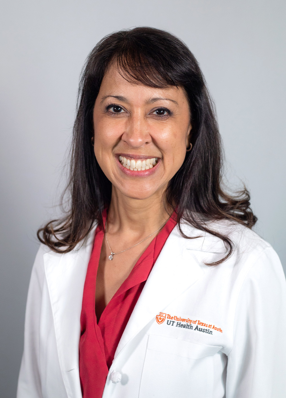 Dr. Rosario DeLeon wearing a white coat and smiling in front of a white backdrop.