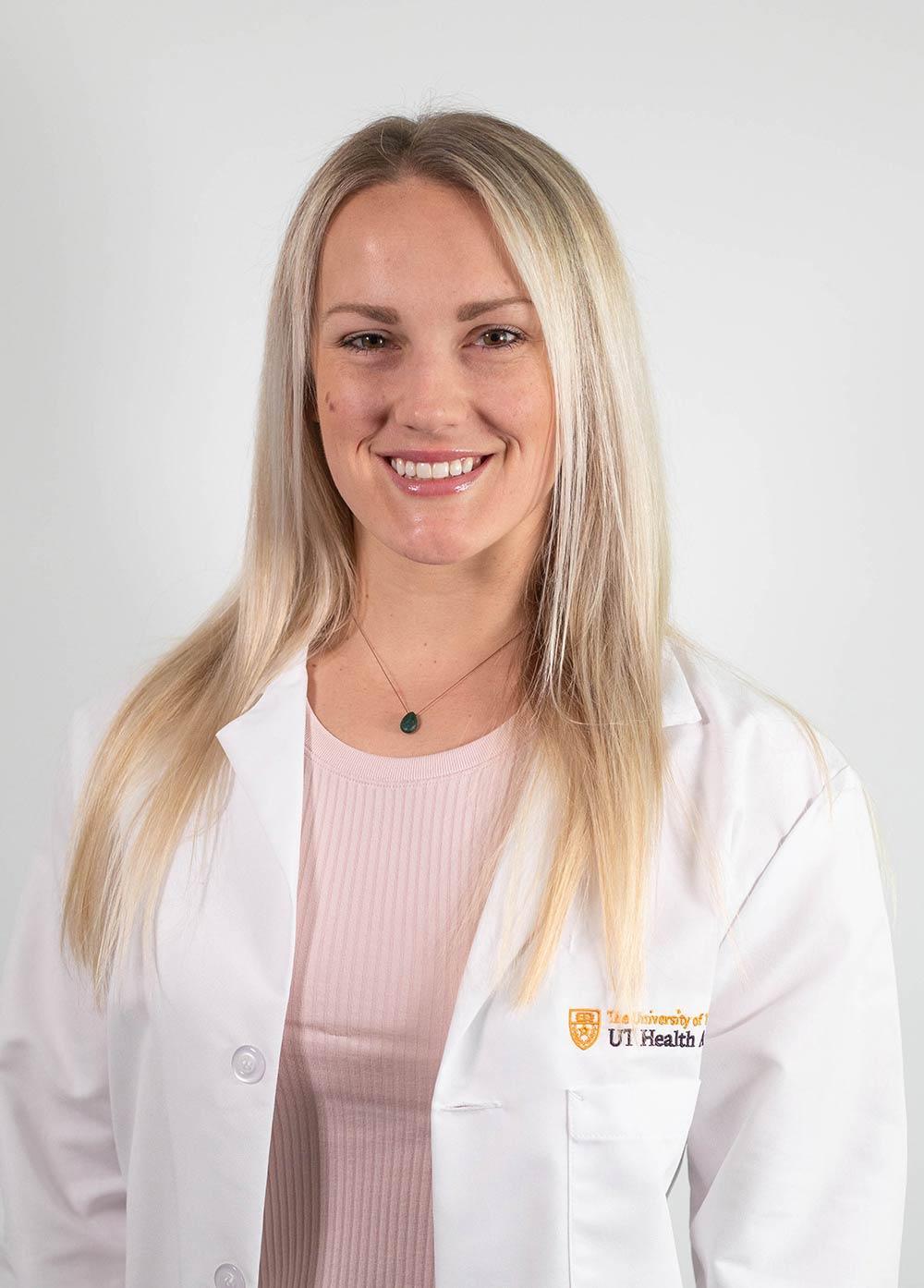 Dr. Samantha Vogel wearing a white coat and smiling in front of a white backdrop.