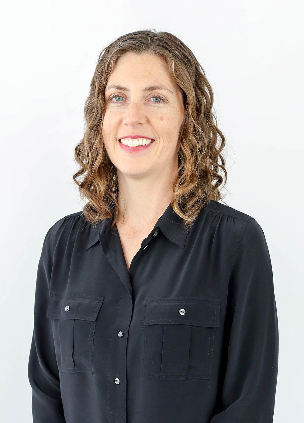 Registered nurse Sarah Campbell, RN, wearing a dark colored blouse and smiling in front of a white backdrop.