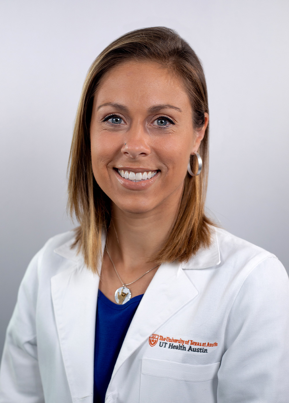 Child and adolescent psychologist Sarah, Schofstall, PhD, wearing a white coat and smiling in front of a white background.