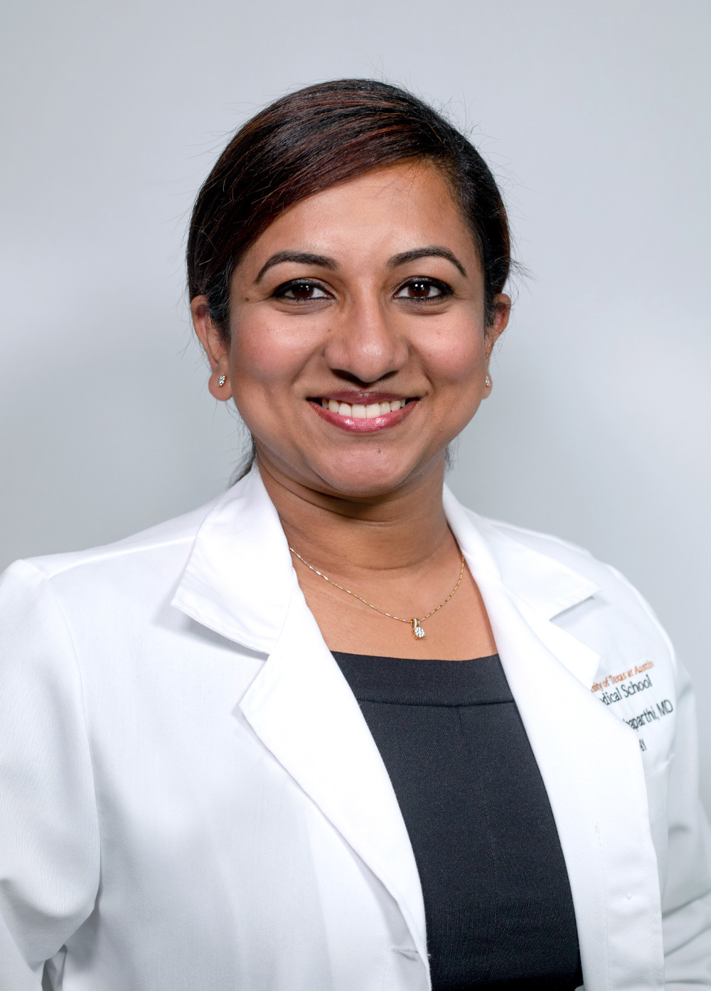 Pediatric neurologist Sireesha Chinthaparthi, MD, wearing a white coat and smiling in front of a white backdrop.