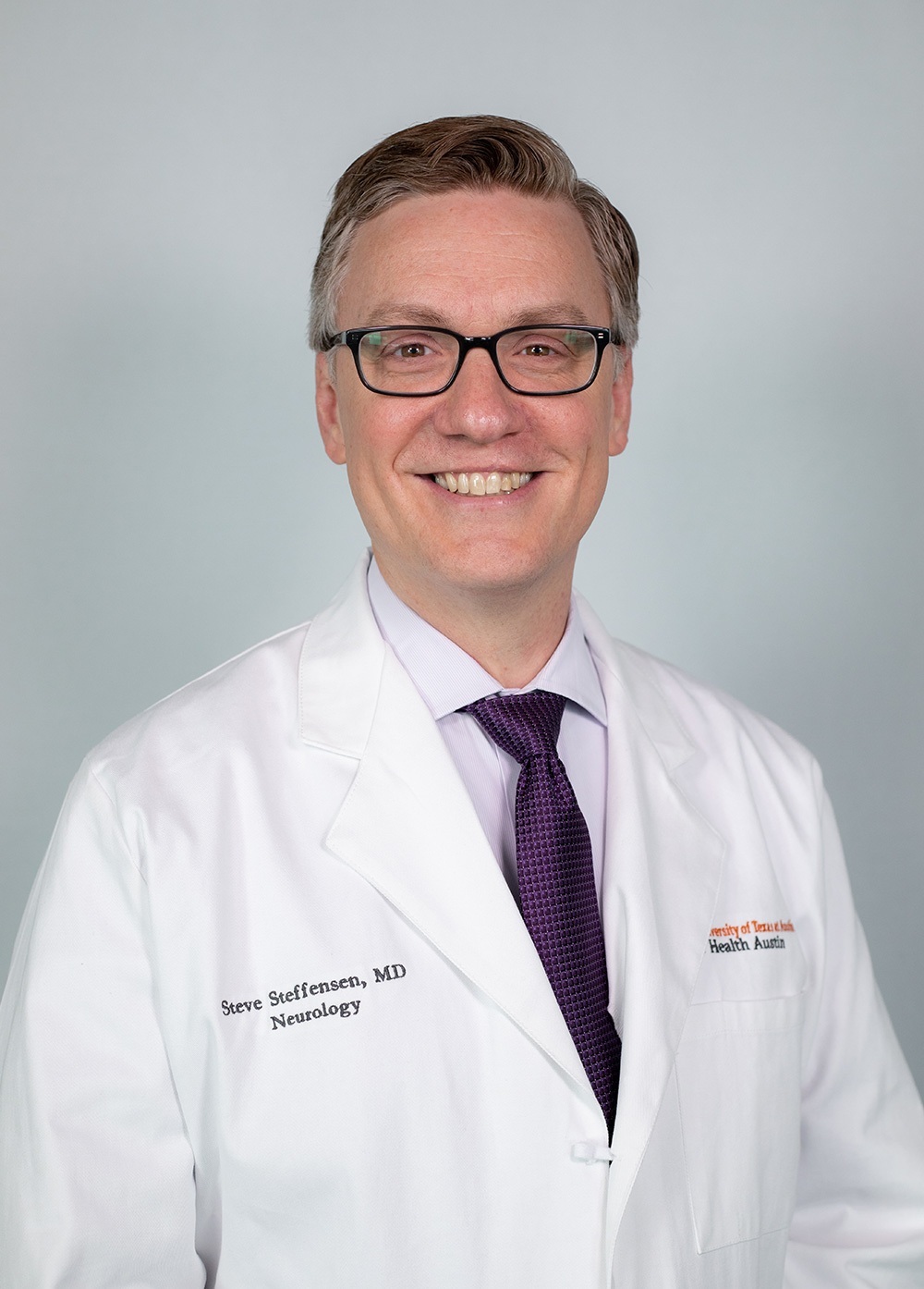 Dr. Steve Steffensen wearing a white coat and smiling in front of a white backdrop.