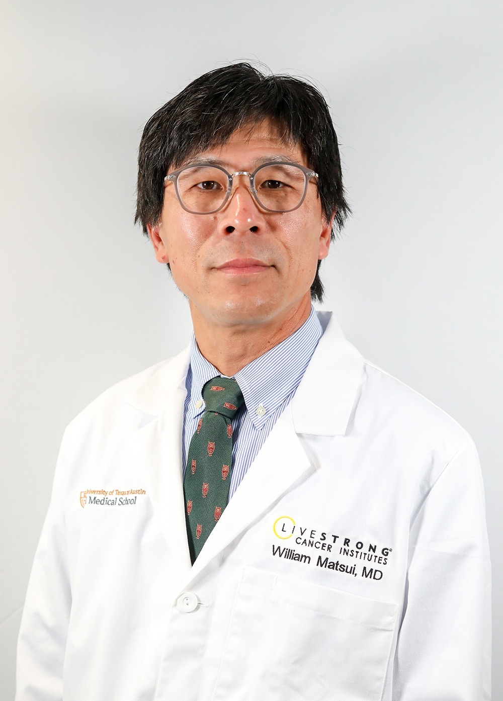 Dr. William Matsui wearing a white coat and posing in front of a white backdrop.