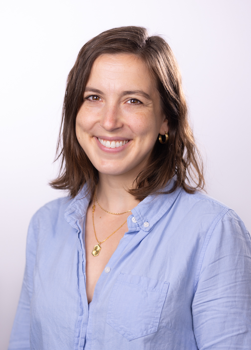 Abigail Leff wearing a blue blouse and smiling in front of a white backdrop.