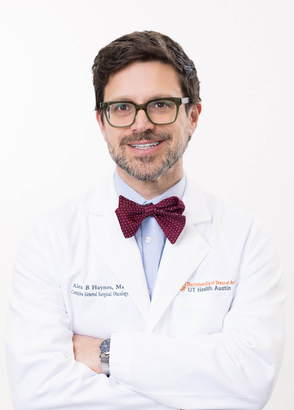 Dr. Alex B. Haynes wearing a white coat and smiling in front of a white backdrop.