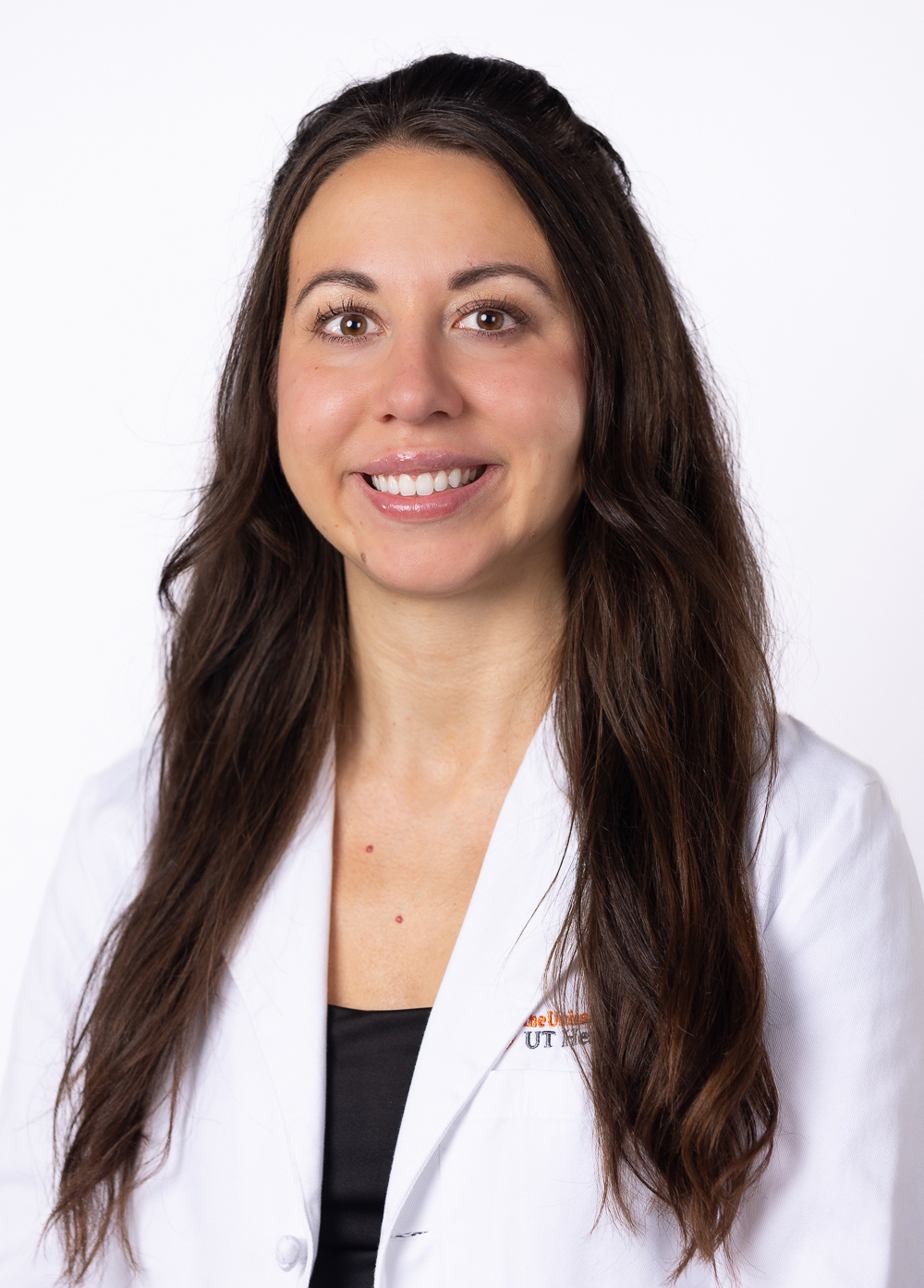 Physician assistant Amanda Ketusky, MSPAS, PA-C, smiling in front of a white background. She is wearing a white coat with an embroidered UT Health Austin logo.