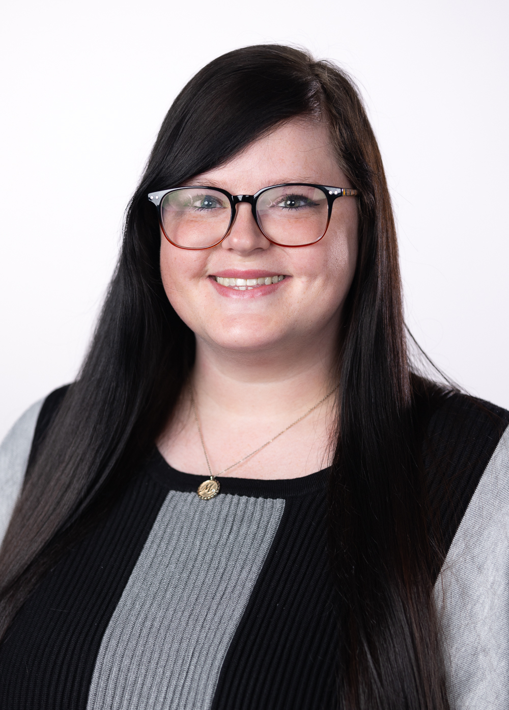 Medical assistant Amanda Garner wearing a black and gray sweater and smiling in front of a white backdrop.