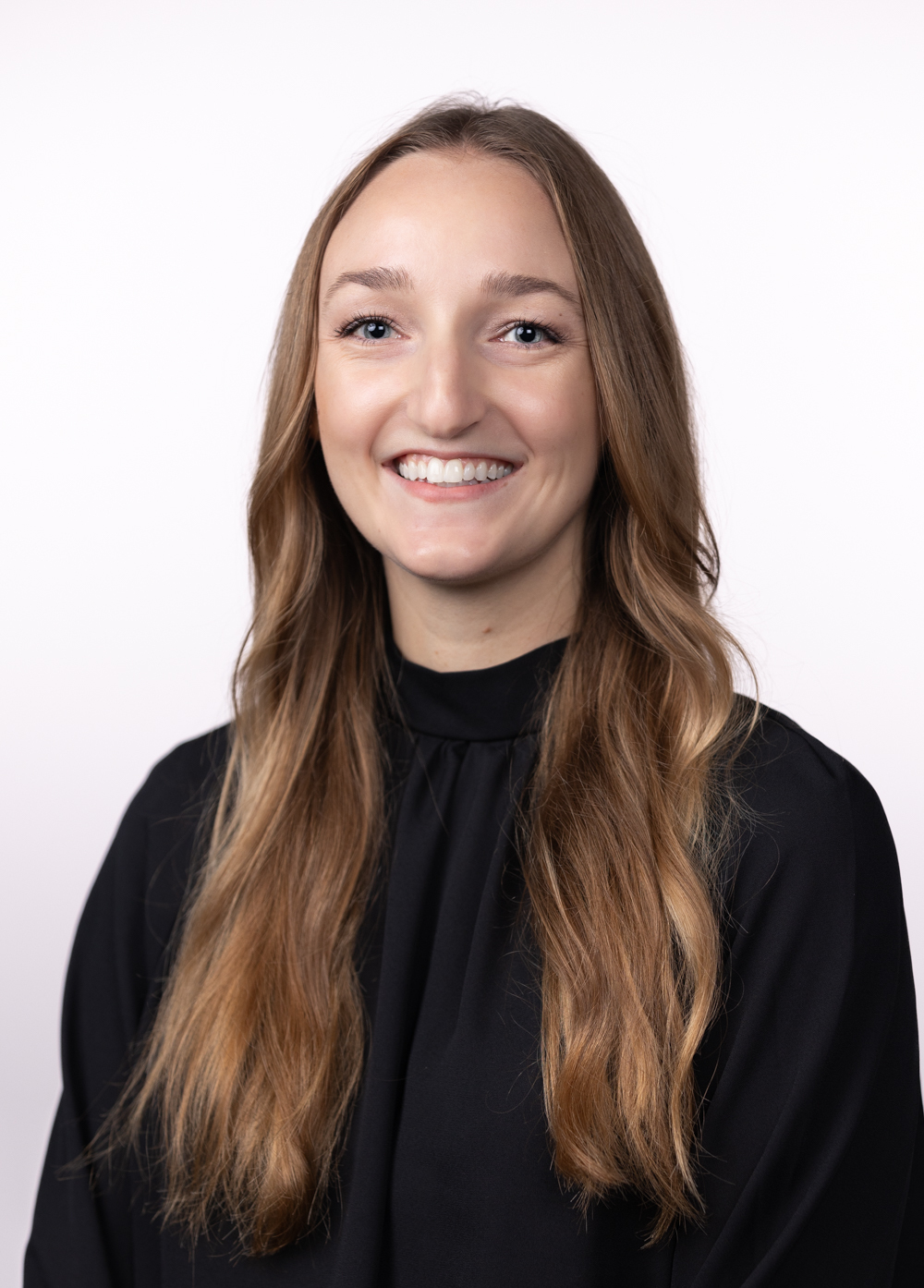 Anastasia Dixon, LMSW, smiling and looking at the camera against a white backdrop.  She is wearing a black blouse.