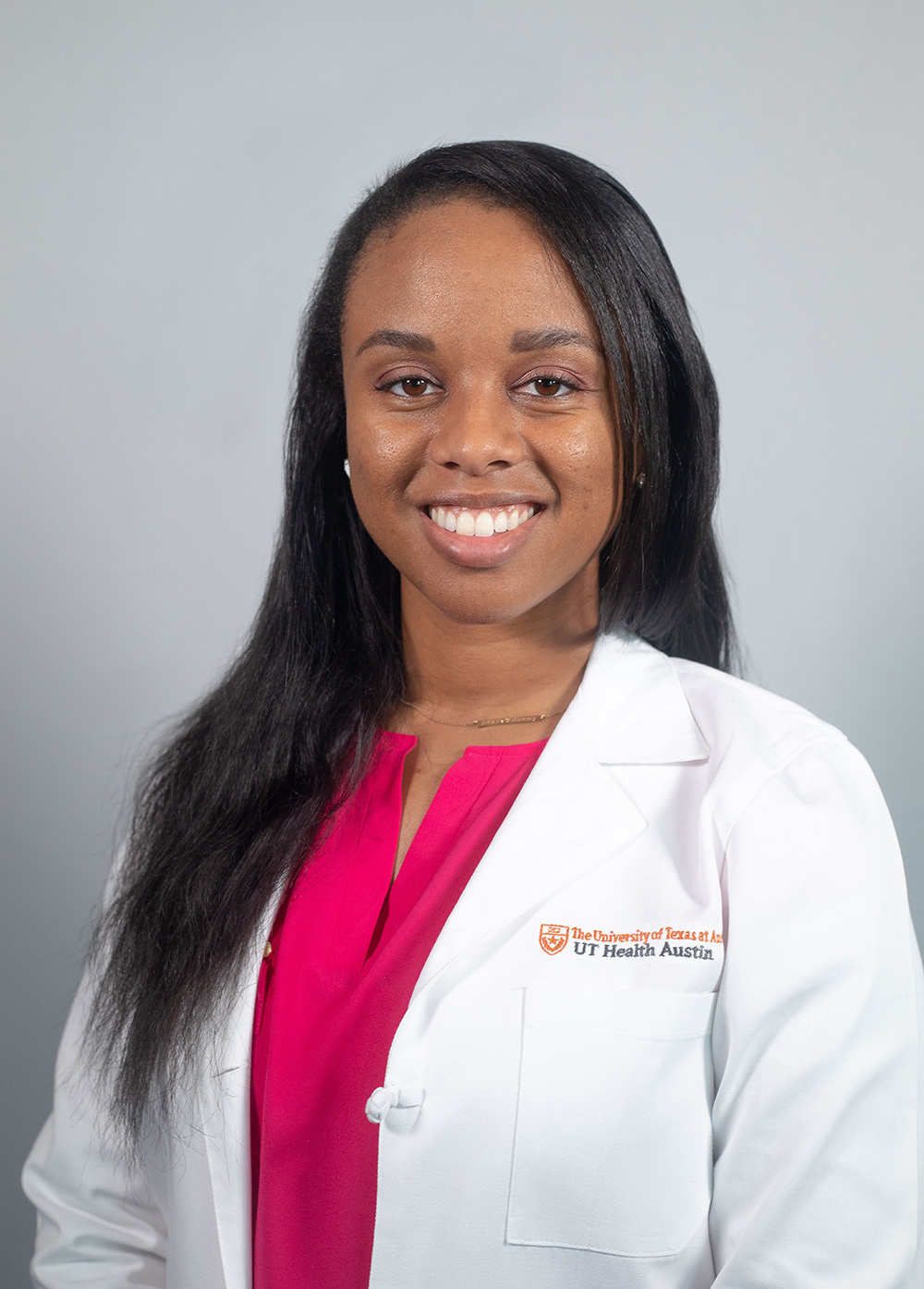 Pediatric nurse practitioner Ashley Griffin MSN, RN-BC, CPNP-AC, CCRN, wearing a white coat and smiling in front of a white backdrop.