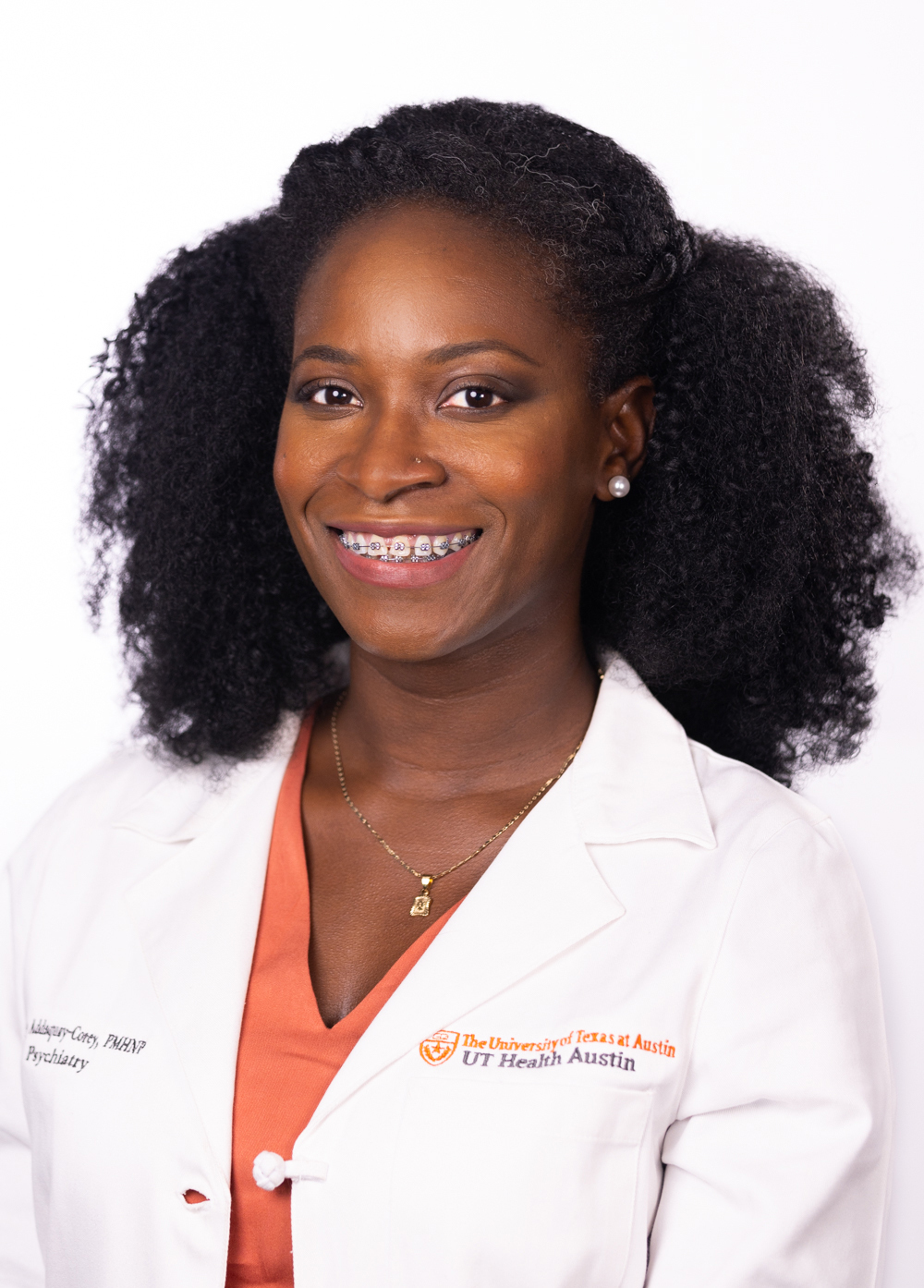 Audrey Addaquay Corey wearing a white coat and smiling in front of a white backdrop.