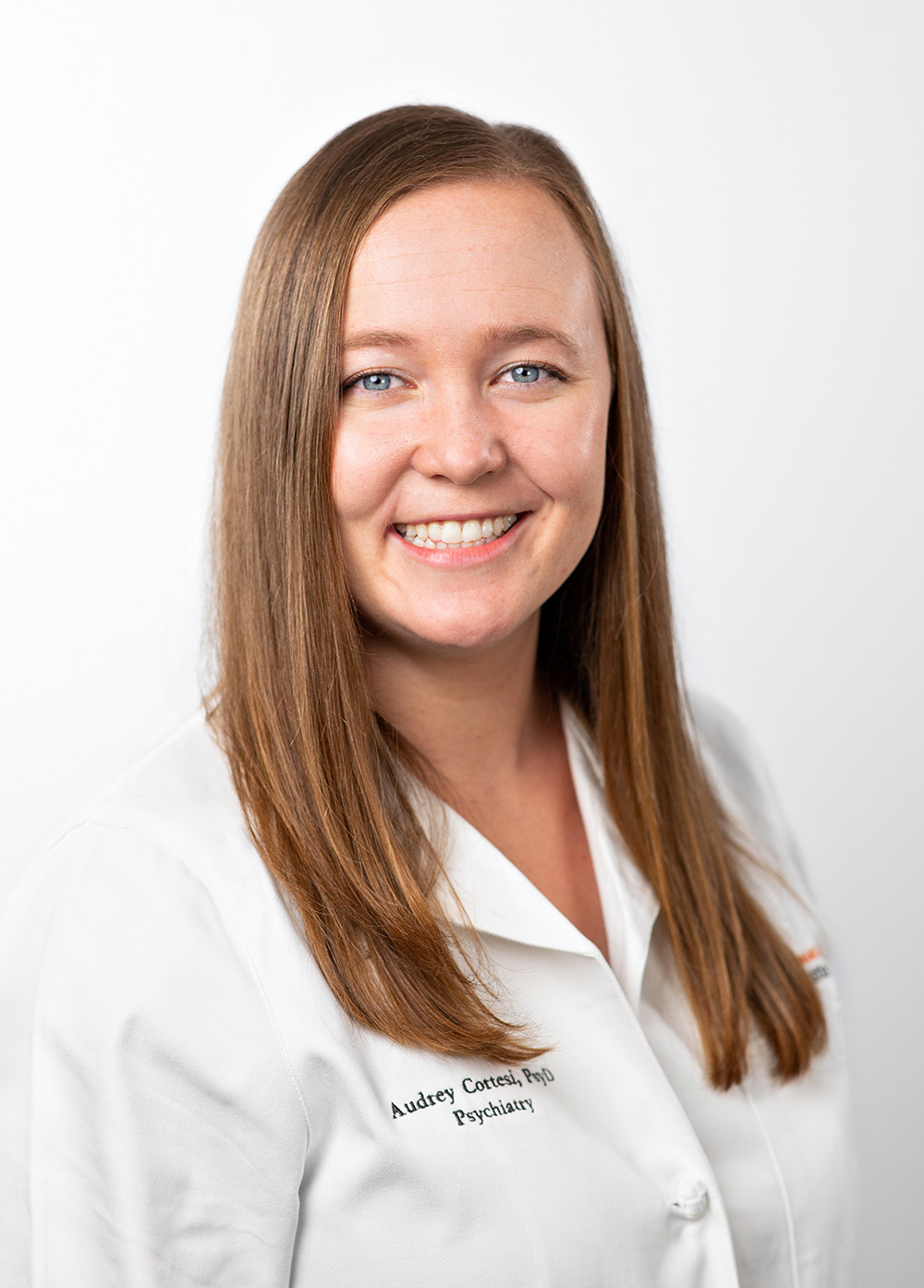 Pediatric psychologist Audrey Cortesi, PsyD, wearing a white coat and smiling in front of a white backdrop.